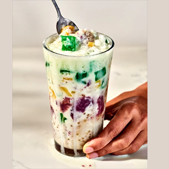 Vibrant glass of Filipino halo-halo dessert layered with shaved ice, ube ice cream, and leche flan